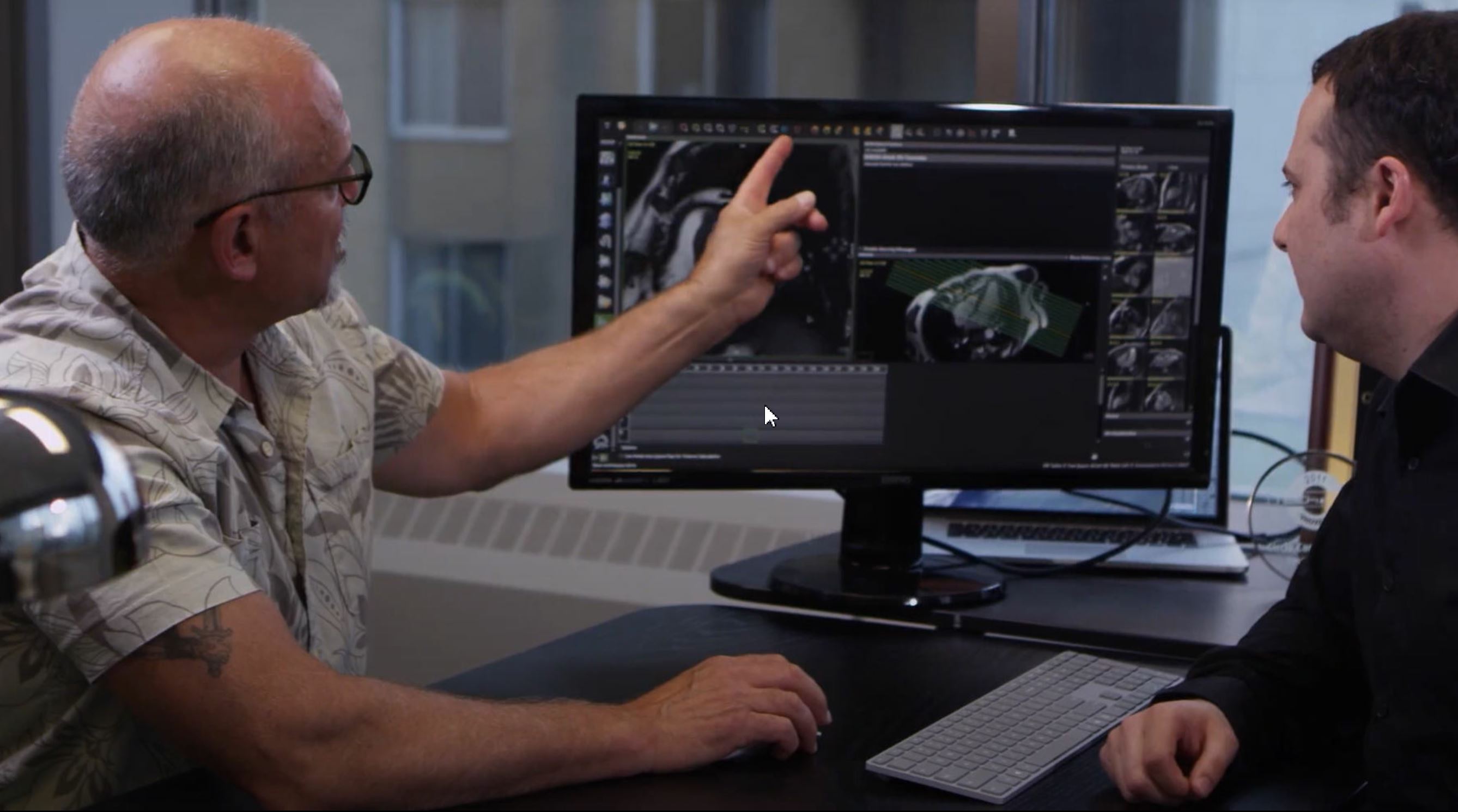 Deux hommes regardent une scanographie numérique d’un cœur sur un écran placé entre eux.